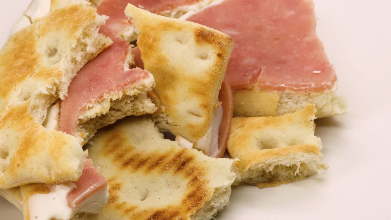 sobras de sándwich, sándwich de jamón y queso, desperdicios de alimentos sólidos girando sobre fondo de superficie blanca, primer plano macro