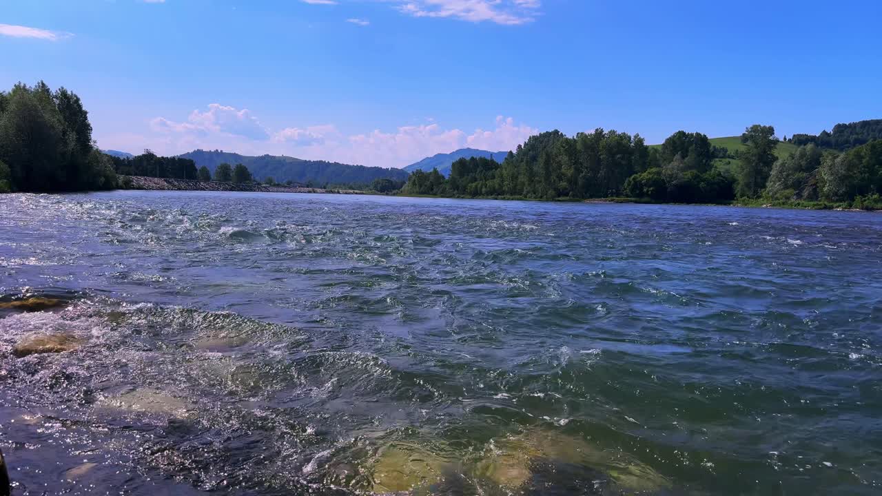 A Tranquil River Scene with Flowing Water and Lush Greenery Beneath a Bright Blue Sky, Showcasing the Beautiful Natural Landscape and Serene Atmosphere