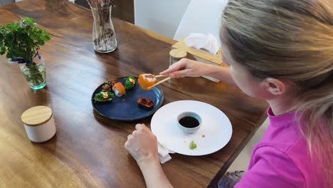 mujer comiendo sushi en una mesa