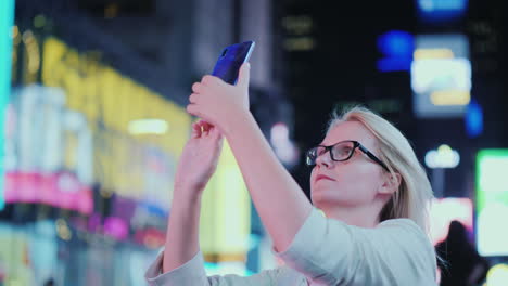 portrait of an attractive woman taking pictures of sights in times square it stands on the backgroun