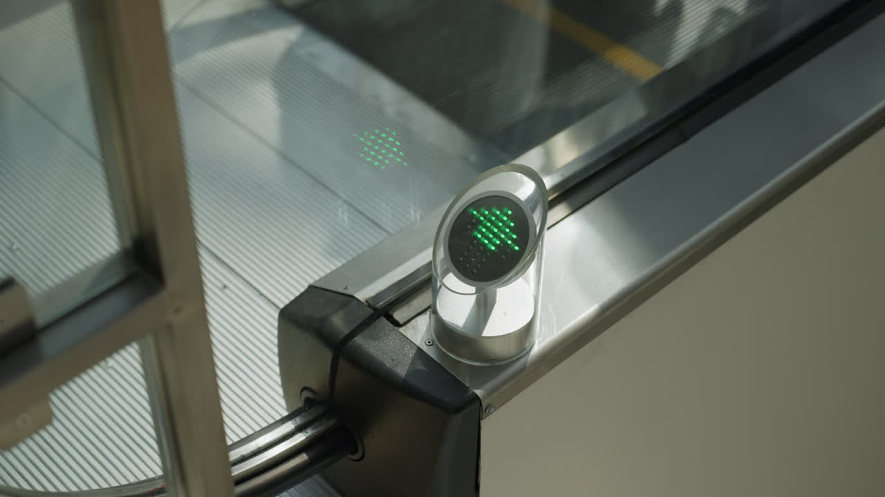 Close-up view capturing an escalator in a mall with people going down. The focus is on the mechanical details and the reflections of people on the metal surface