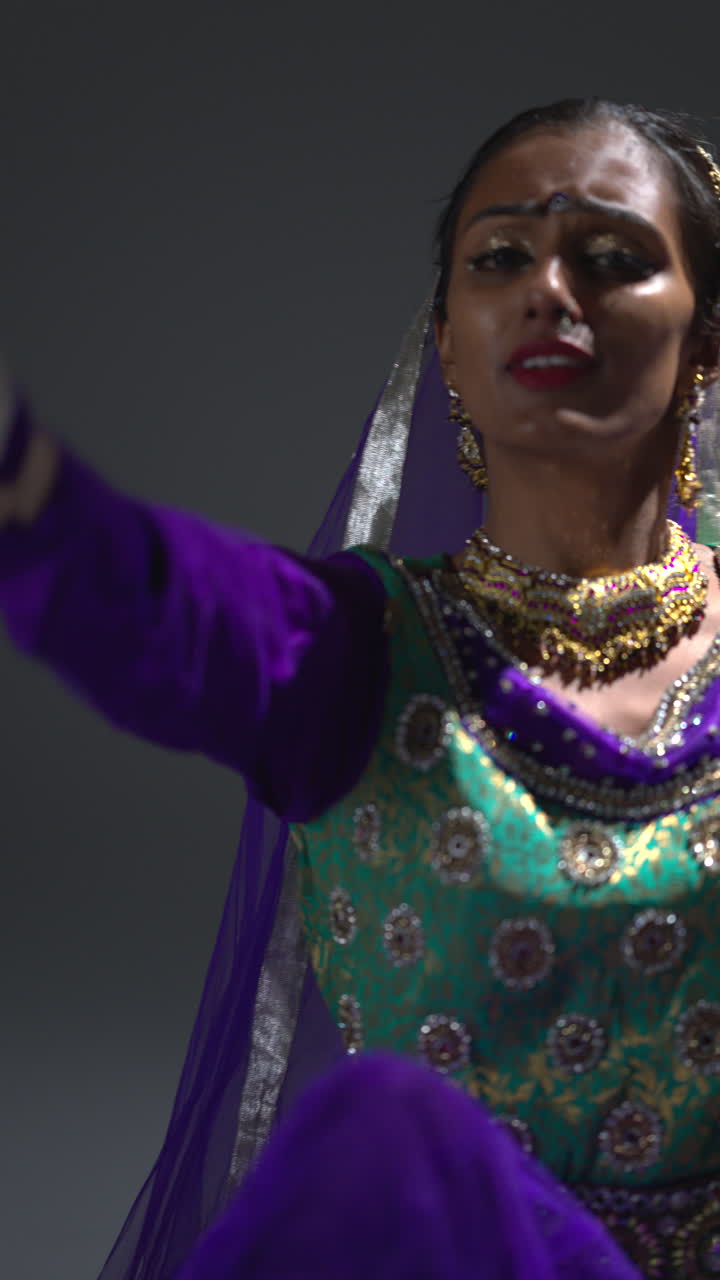 video vertical de una bailarina de kathak femenina realizando un baile vestida con un vestido tradicional indio sentada en el suelo en el centro de atención 4