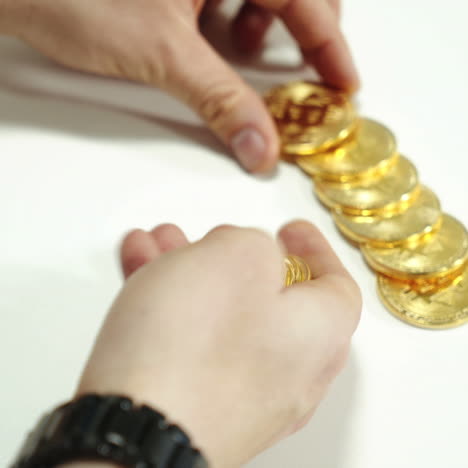 men's hands spread the gold coins bitcoin on the table. cryptocurrency in the form of gold.