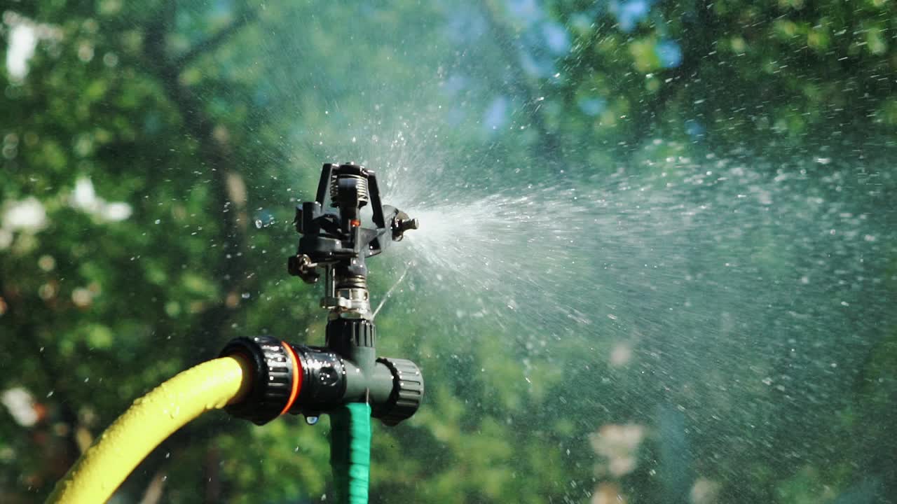 Slow motion. Garden Irrigation Sprinkler watering lawn. Close-up shot