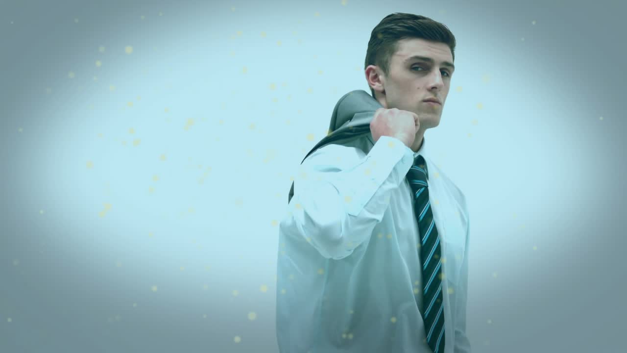 Businessman raising suit jacket behind shoulder and pulling onto back as golden particles swirling