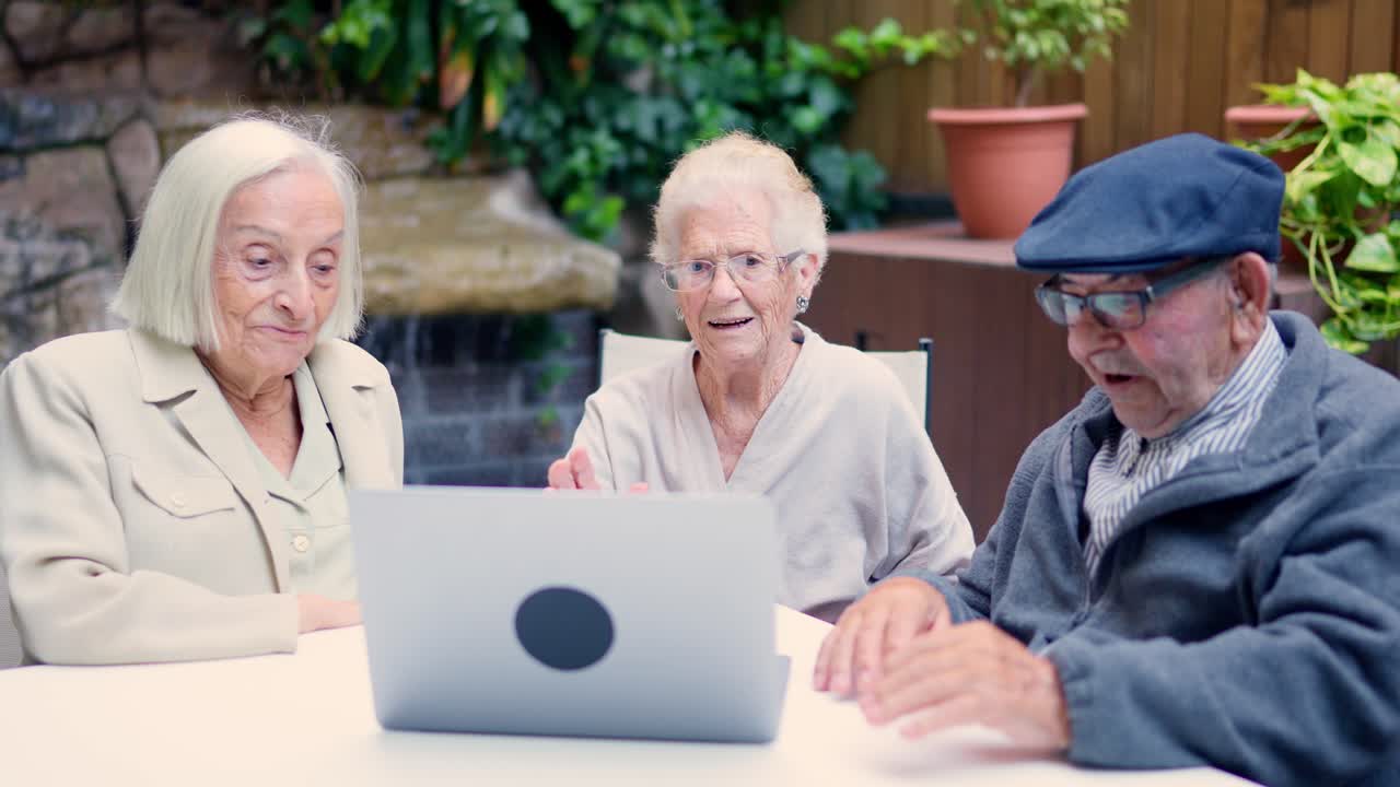 Elderly people using a laptop for a video call in a garden