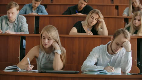 En-El-Aula,-Estudiantes-Multiétnicos-Escuchando-A-Un-Profesor-Y-Escribiendo-En-Cuadernos.-Los-Jóvenes-Inteligentes-Estudian-En-La-Universidad.