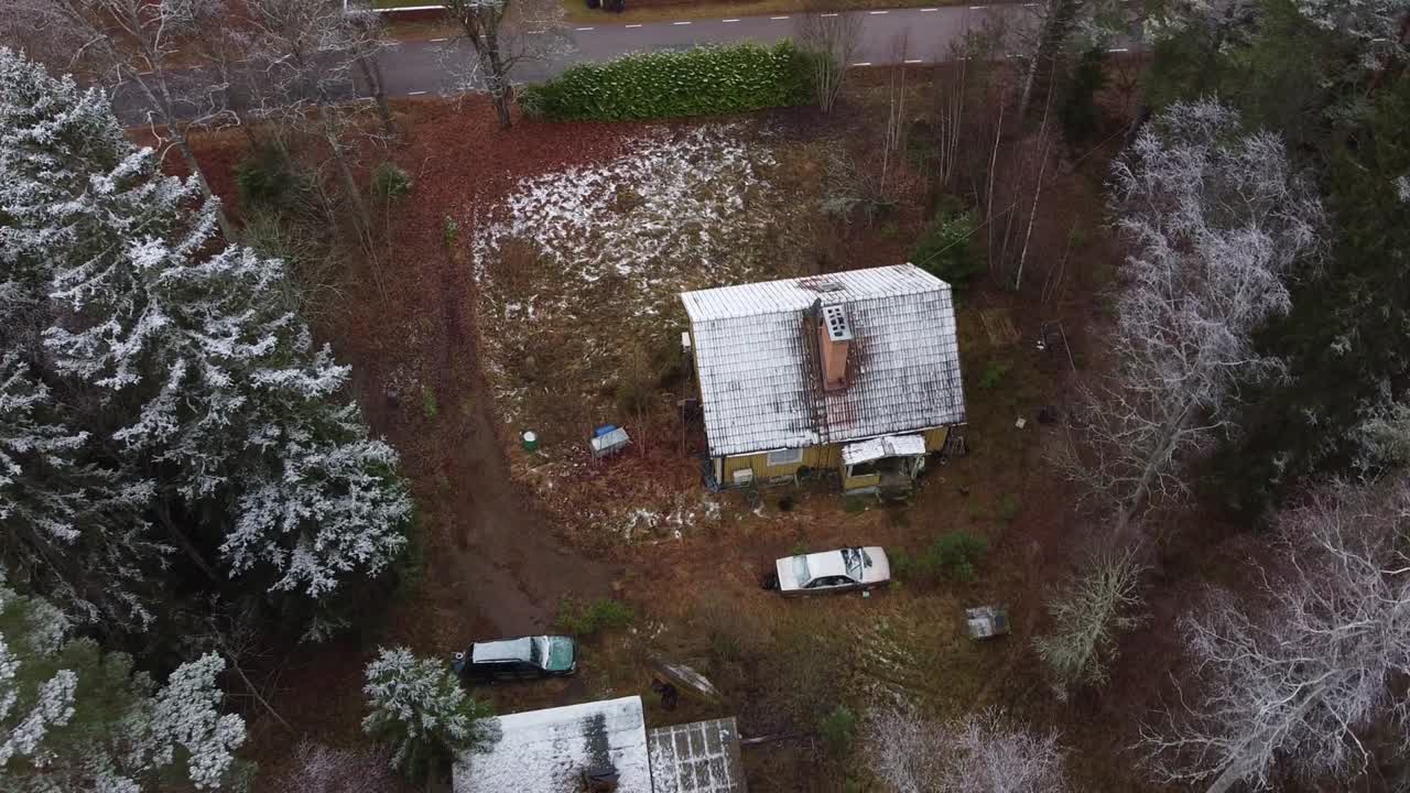 toma de establecimiento de una casa abandonada en un pueblo durante el invierno y dos autos que no funcionan en un patio