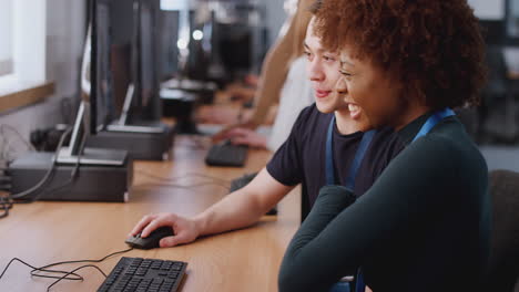 group of college students studying computer design sitting at monitors in classroom