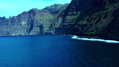 blue sea water with smooth waves under high mountains in tenerife island, spain