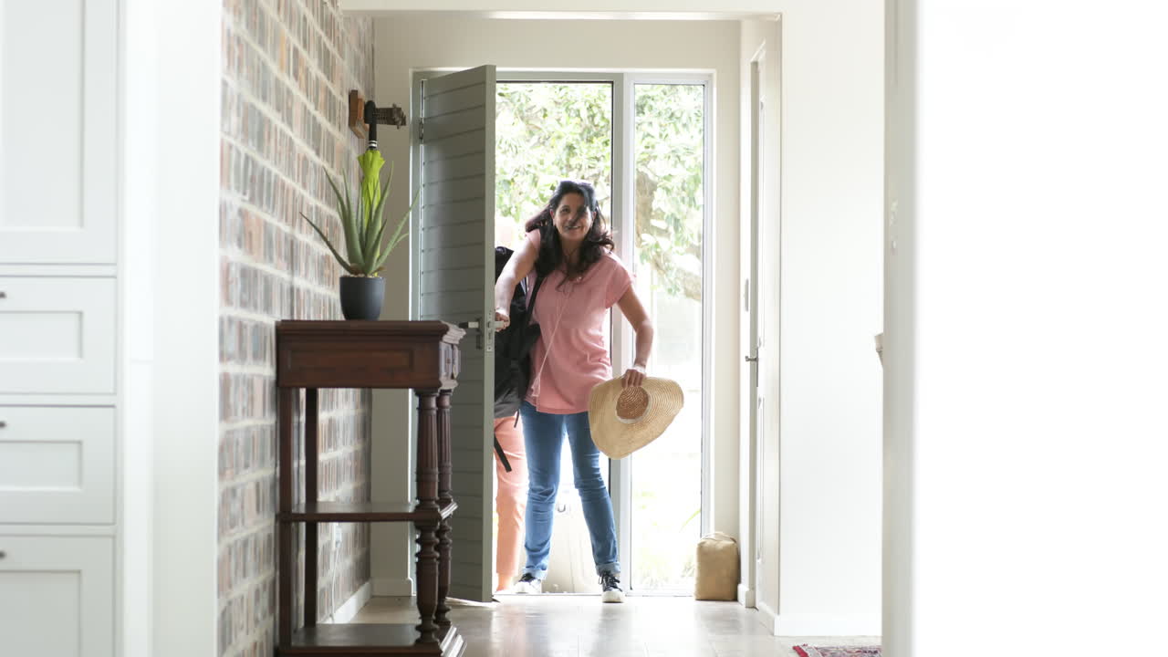 Mujeres mayores diversas y felices abriendo la puerta y entrando a casa en un día soleado, a cámara lenta.