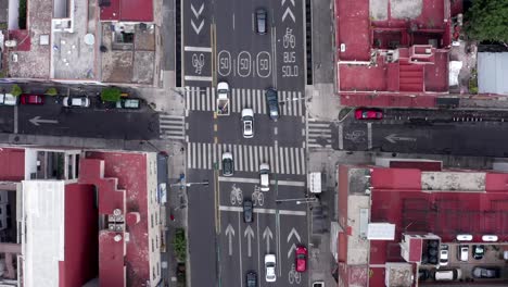 Vuelo-Directamente-Sobre-El-Tráfico-De-Automóviles-Que-Viaja-En-La-Calle-Felix-Cuevas-En-El-Centro-De-La-Ciudad-De-México,-Con-Pasarela,-Paso-De-Peatones,-Flechas-Blancas-Direccionales,-Señales-Y-Líneas-De-Bicicletas,-Seguimiento-Aéreo-Aéreo