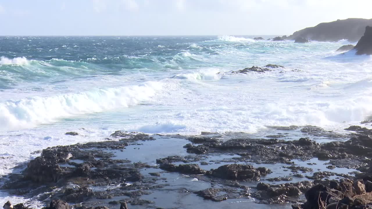 강력한 파도가 바위가 있는 해변에 부히고
