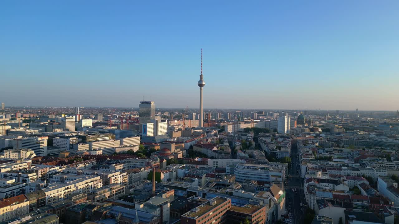 Berlin tv tower standing tall over the tower and red town hall, bathed in the warm glow of golden hour. Majestic aerial view flight fly reverse drone