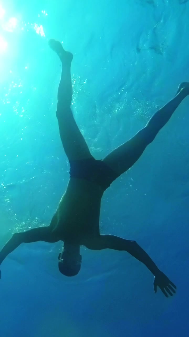 Man swimming and doing a somersault underwater