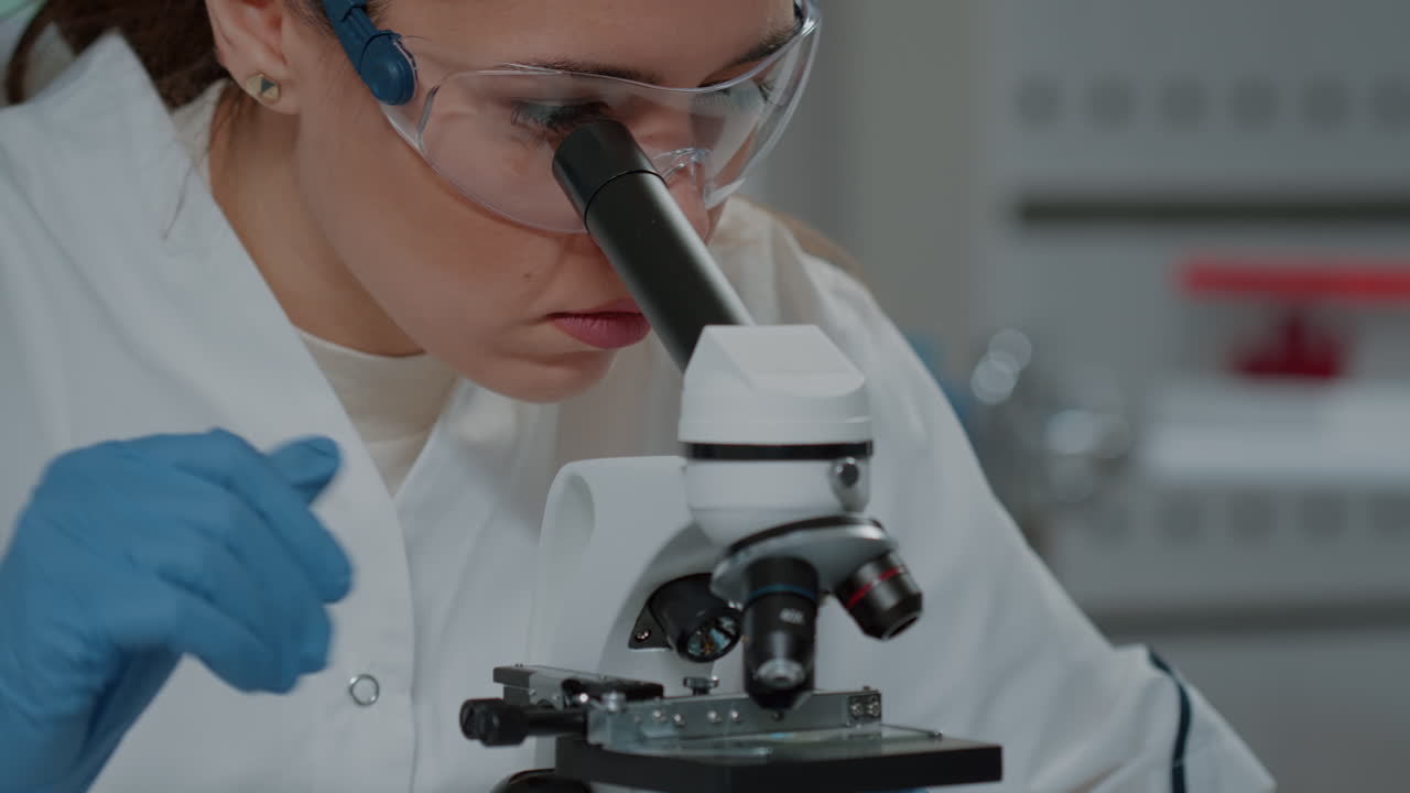 Scientist looking through microscopic lens to work on experiment