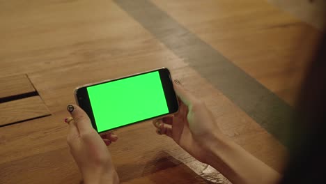 mujer con un teléfono inteligente en la mano con una pantalla verde en blanco leyendo noticias en el móvil.