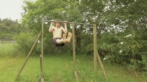 fit athletic young man doing l-sit pullups on home gym outdoors