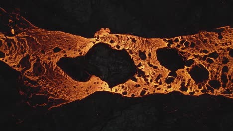 drone flying over golden magma running through black rocks