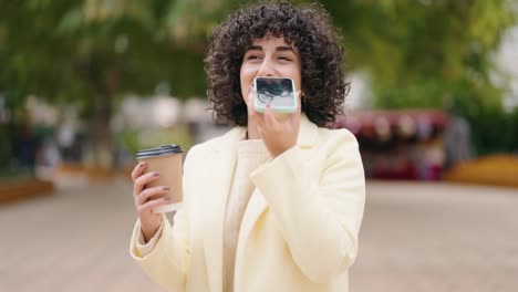 young woman talking on the smartphone drinking coffee at park