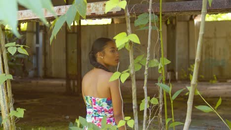 una joven reina caribeña gira y sonríe mientras se sienta en las ventanas de un almacén abandonado