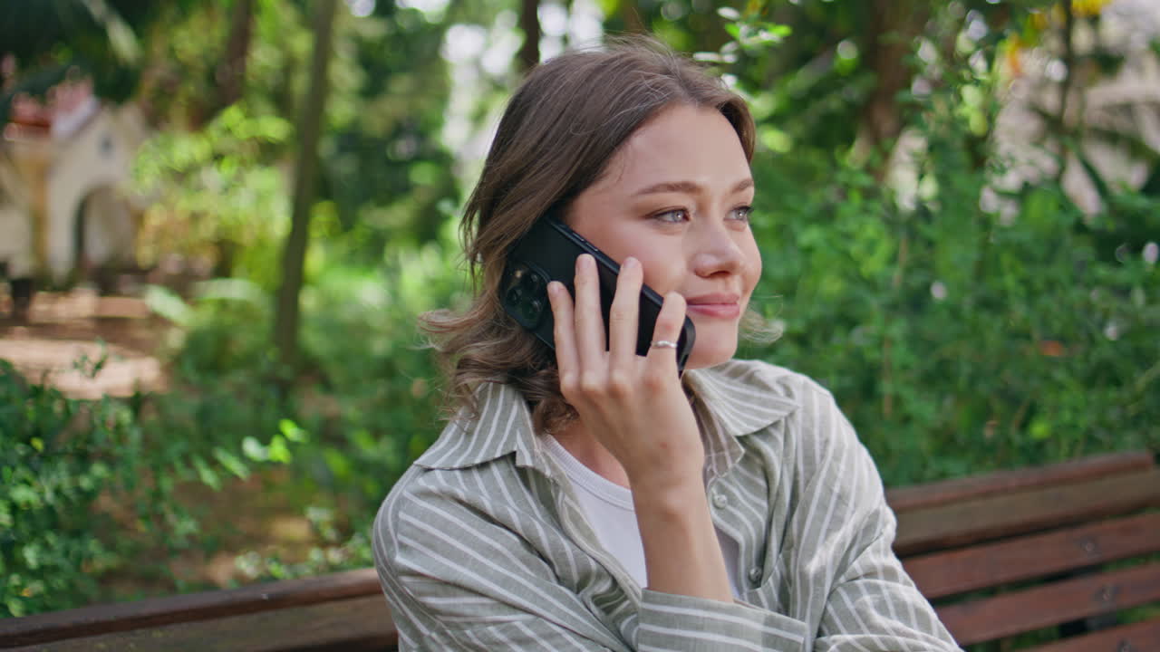 Smiling woman talking smartphone sitting in serene park closeup. Happy girl