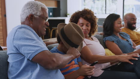 Familia-Afroamericana-Multigeneracional-Relajándose-En-Casa-Sentados-En-El-Sofá-Viendo-La-Televisión-Juntos