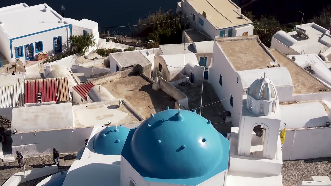 santorini oia thirasia ciudad cúpula azul iglesia seguimiento e inclinación drone aéreo
