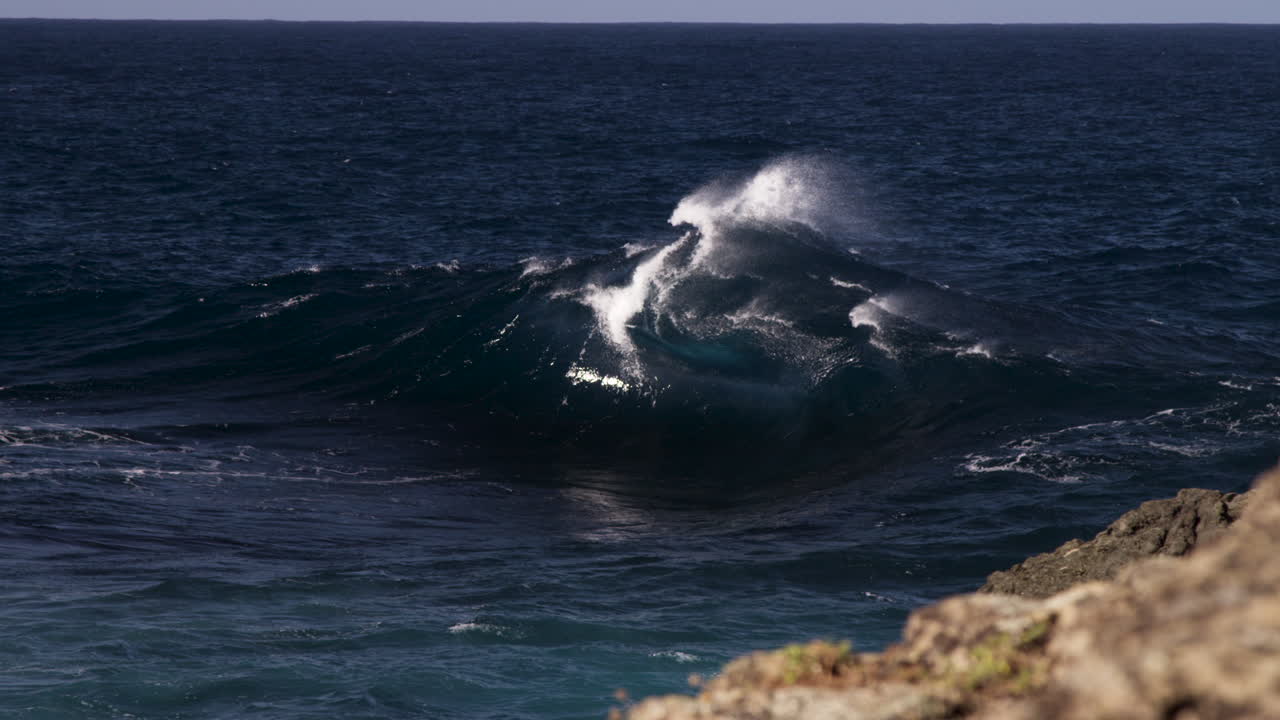una ola pico rompe en forma de marco no lejos de la línea de la costa rocosa