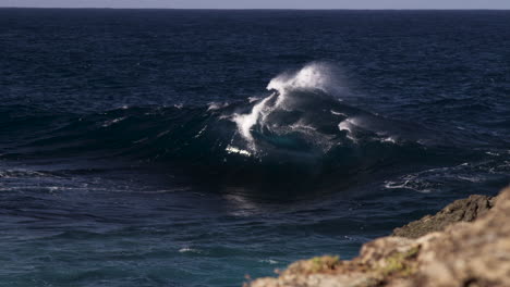 una ola pico rompe en forma de marco no lejos de la línea de la costa rocosa