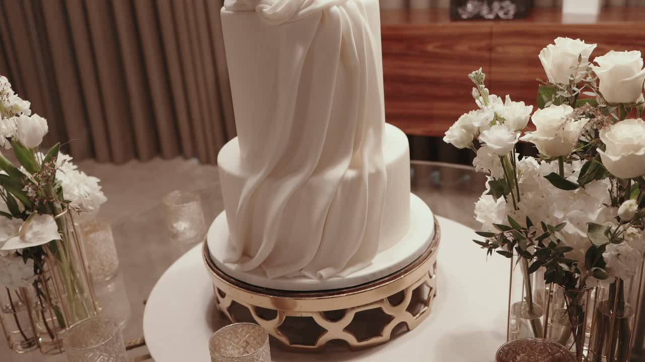 luxury wedding cake on ornate stand with white flowers and glass details