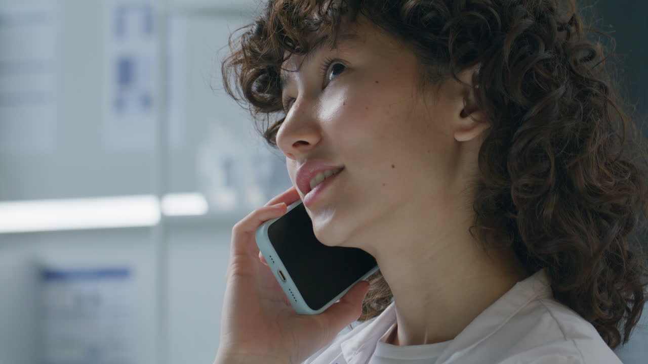 Young Female Lab Technician Talking on Phone at Workplace