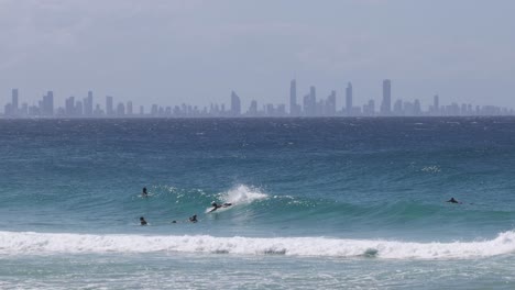 surfers catching waves with city skyline backdrop