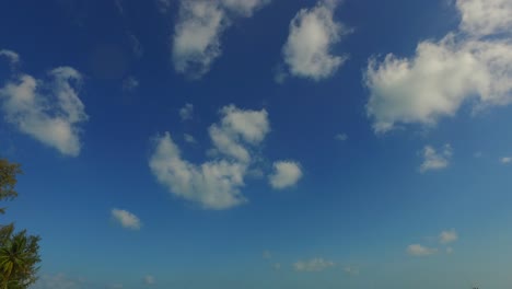 Beautiful-bright-blue-sky-with-white-clouds-over-turquoise-lagoon-with-anchored-boats-near-sandy-exotic-beach,-Thailand