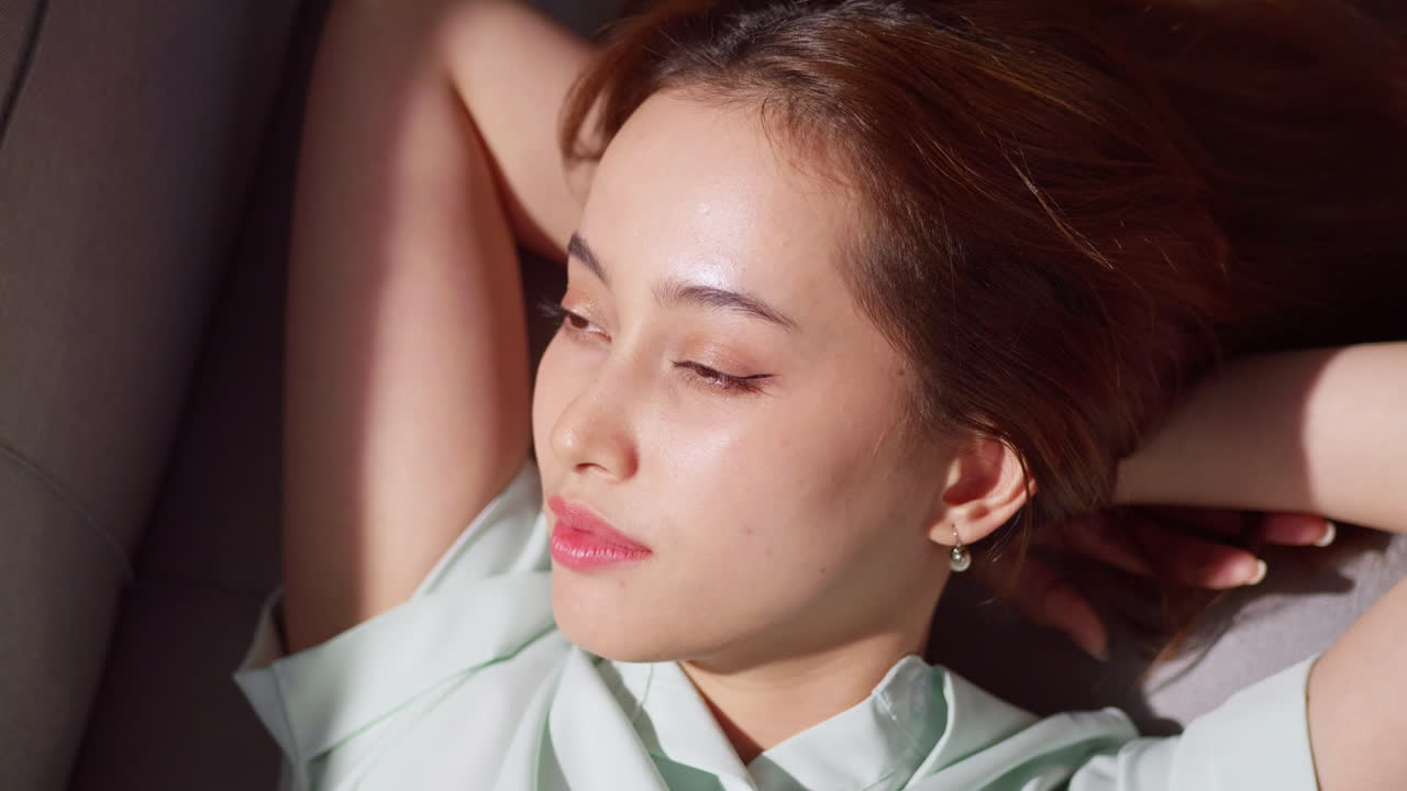 A serene portrait capturing a young woman enjoying a moment of relaxation indoors.
