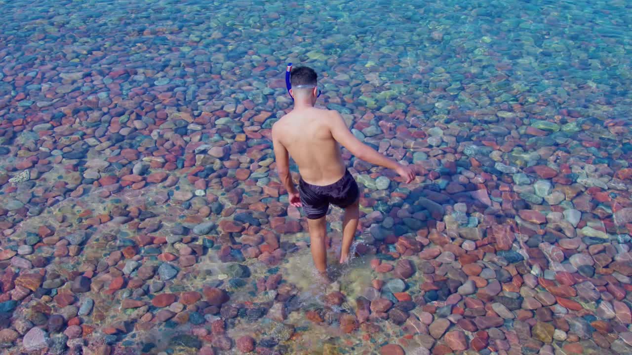 un ragazzo che si sta dirigendo verso il mare per fare snorkeling