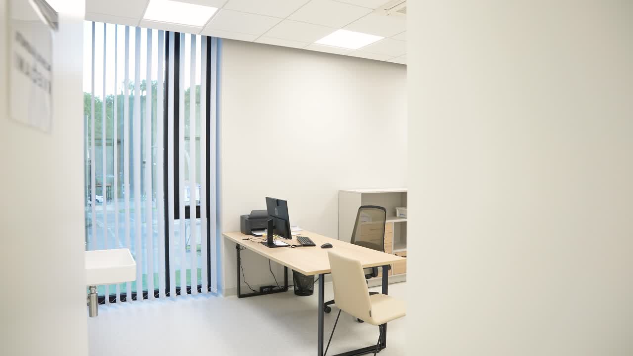 Bright and clean modern medical consultation room with a desk, computer, and examination bed, designed for patient checkups and private healthcare consultations