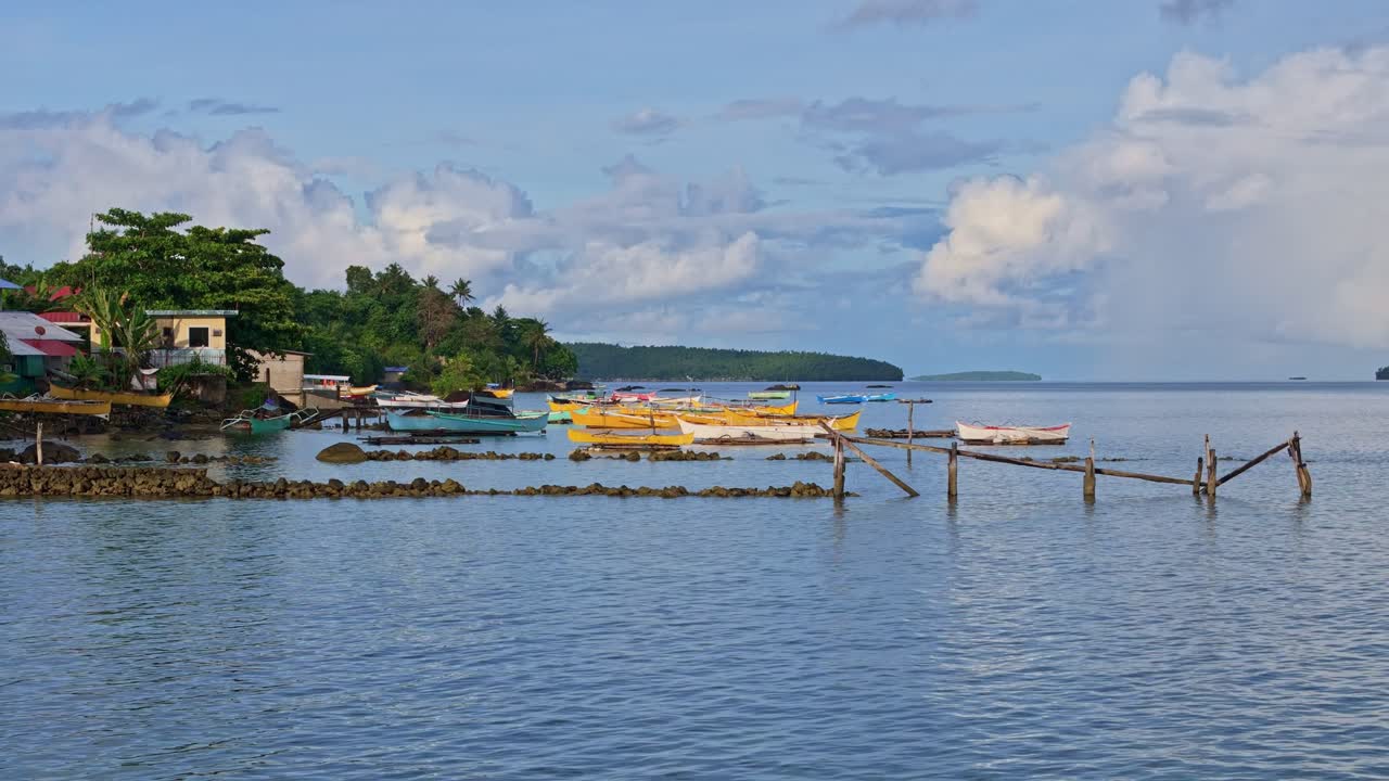 A tranquil static shot of traditional fishermen’s boats moored along the shoreline of Dinagat Island, Philippines.
