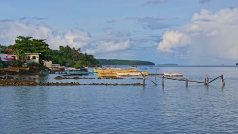 a tranquil static shot of traditional fishermen’s boats moored along the shoreline of dinagat island, philippines.