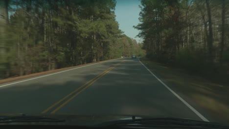 driving down a two-lane road through the autumn woods with passing cars