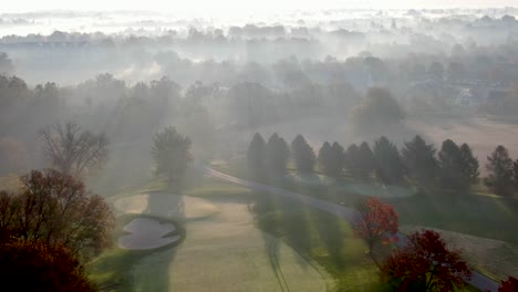 Antena-Ascendente-Revela-Capas-De-Niebla-Iluminada-Durante-El-Amanecer-De-Octubre-Sobre-El-Campo-De-Golf-En-Lancaster-Pa