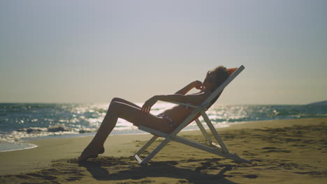 woman sunbathing on beach chair at sunset