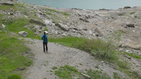 Hiker-man-runs-down-trail-to-view-alpine-lake,-Mont-Cenis-mountain-landscape