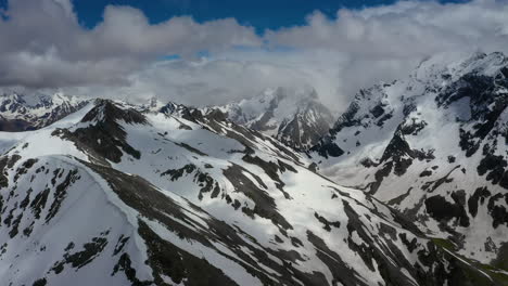 Vuelo-Aéreo-A-Través-De-Nubes-Montañosas-Sobre-Hermosos-Picos-Nevados-De-Montañas-Y-Glaciares.