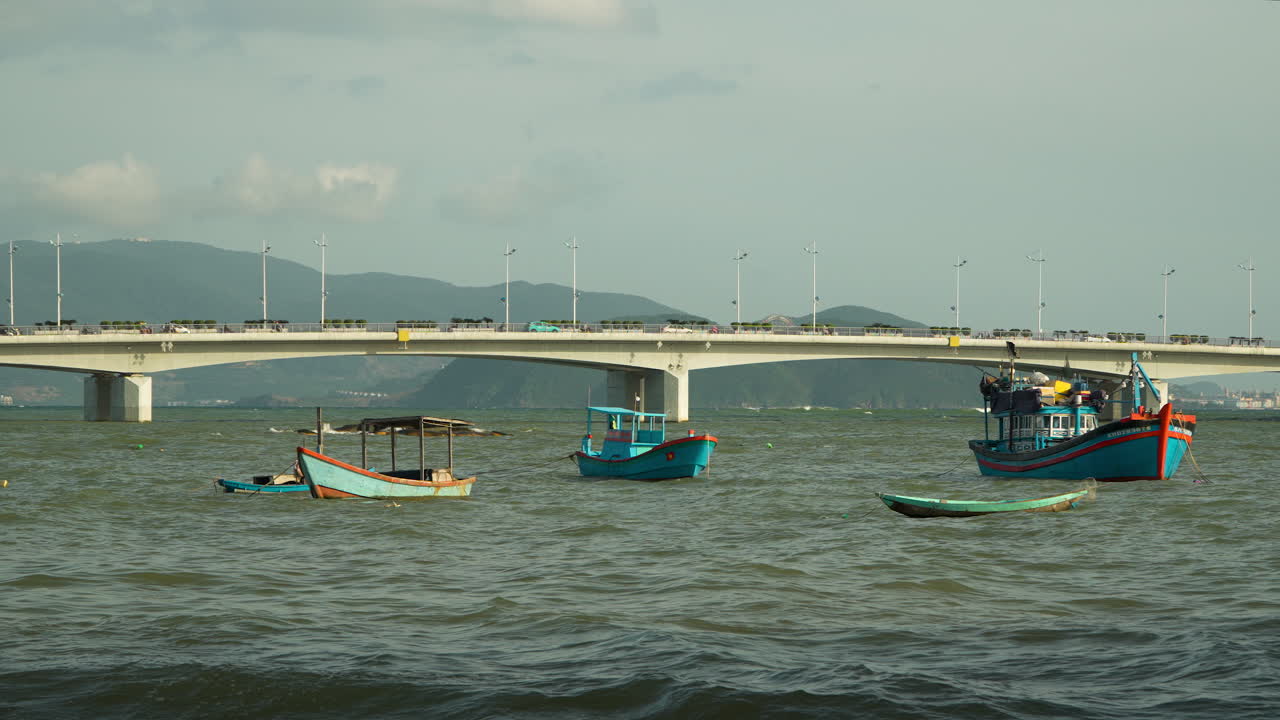 Wooden fishing boats anchor on Cai River water at Cu Lao village coast with Tran Phu Bridge and Mountains in Background, Nha Trang Vietnam