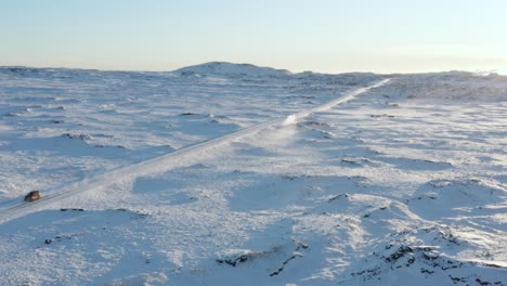 car travels on icy road in winter landscape of iceland with bright sunlight