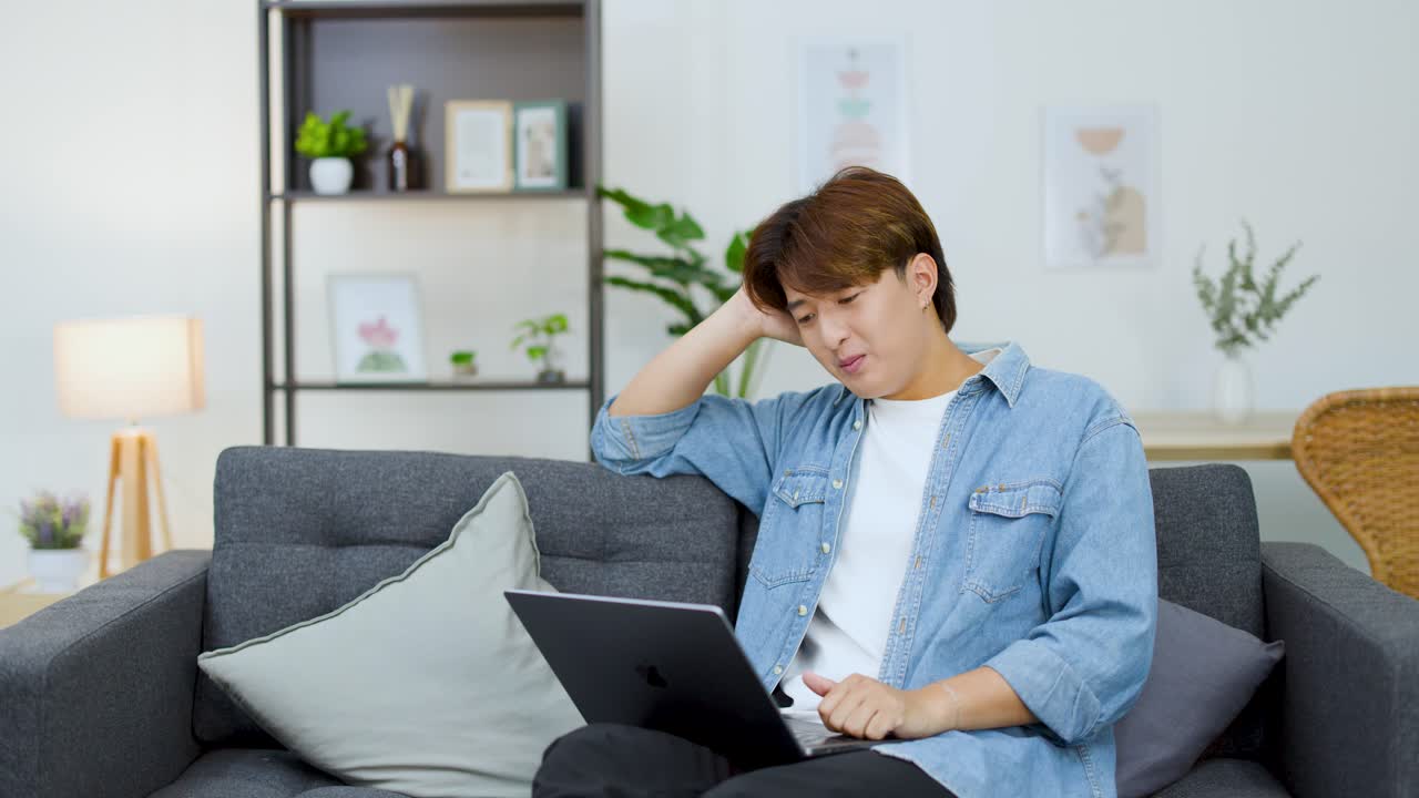 自宅からリモートワークのテレビ会議に参加している、不満そうな若い男性のジェスチャー