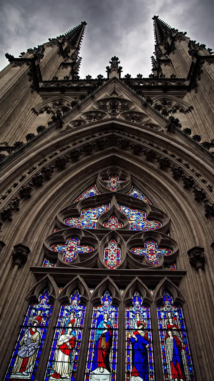 Dramatic low-angle video shot of a Gothic cathedral facade, highlighting intricate stained glass