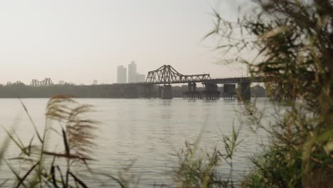 Goldene-Stunde,-Malerischer-Blick-Auf-Die-Long-Bien-Brücke-über-Den-Red-River-Mit-Verschwommenen-Gräsern-Im-Vordergrund,-4K-Auflösung