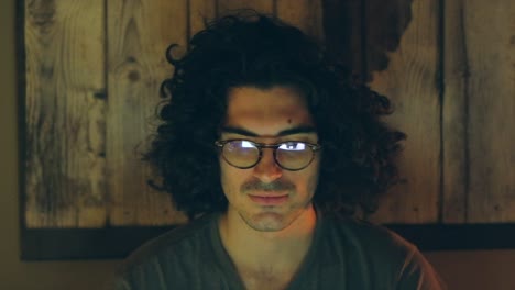 serious man with glasses focused on screen in home office at night